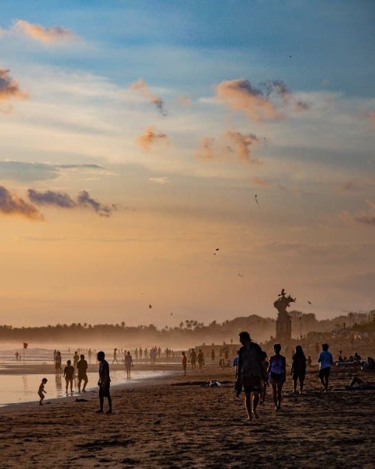 People walking the beach in Canggu at sunset, kites in the sky