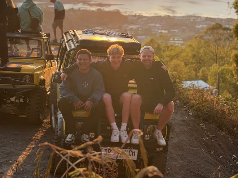 Three friends on the bonnet of their private jeep at the Mount Batur sunrise viewpoint