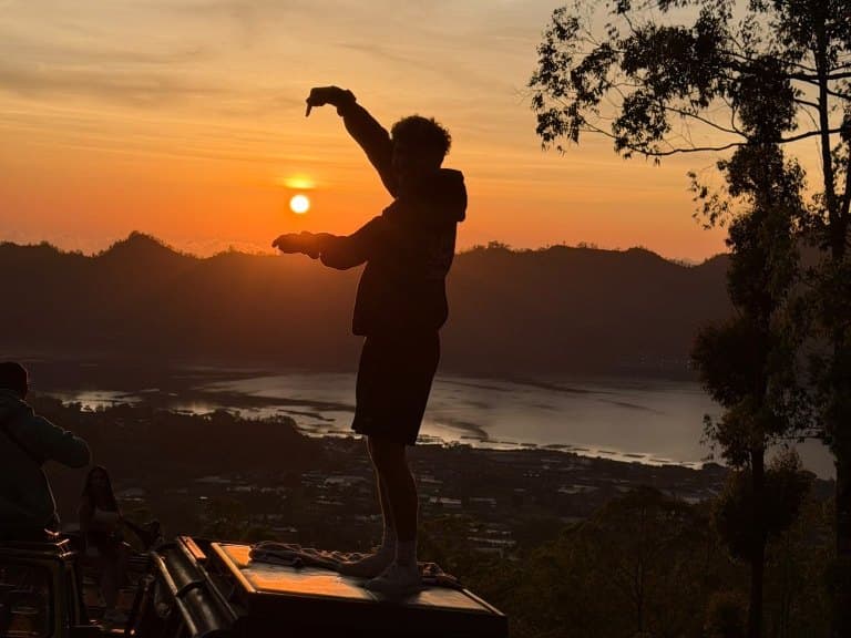 A guest on a jeep roof at the Mount Batur sunrise viewpoint above Lake Batur